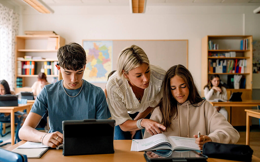 Lehrerin unterstützt Schüler bei Hausaufgaben. Eine Lehrerin hilft Schülern bei den Hausaufgaben im Klassenzimmer.