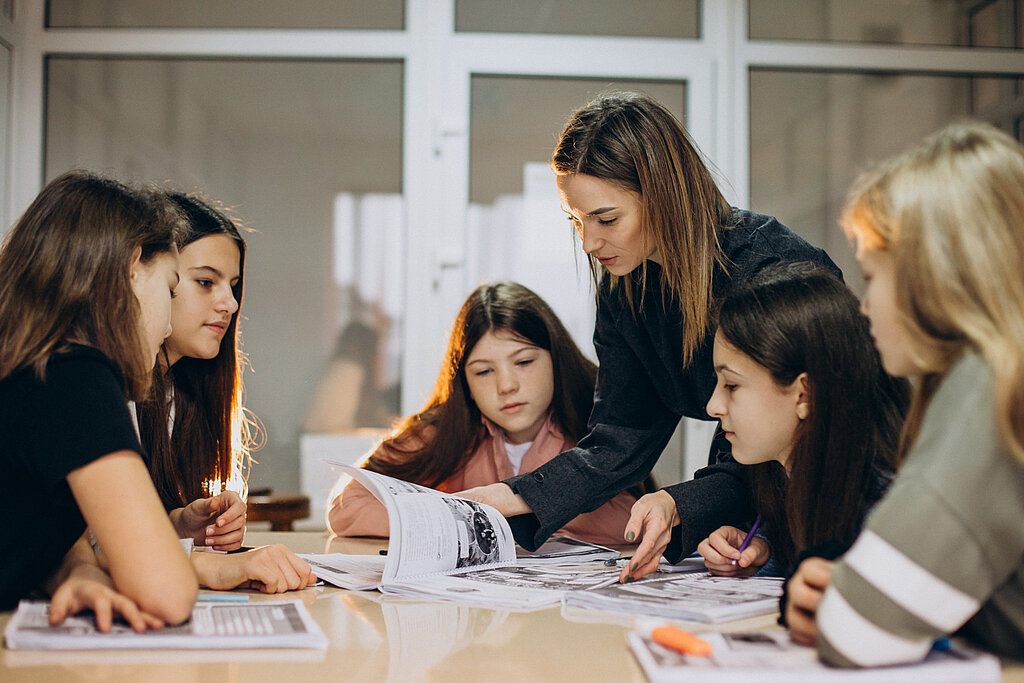 Lehrerin und Schülerinnen sprechen miteinander. Lehrerin und Schülerinnen sprechen miteinander.